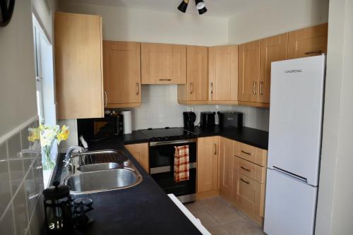 a kitchen with a sink and a white refrigerator at 3 Bed home, Stranmillis, Queens Quarter in Belfast