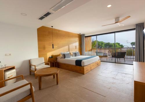 a bedroom with a bed and a table and a chair at Las Gaviotas Suites Hotel & Spa in Playa de Muro