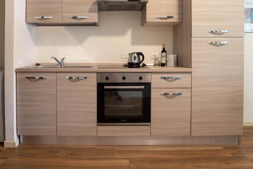 a kitchen with wooden cabinets and a stove top oven at ORA APARTMENT Centro Desenzano del Garda By Case al Lago in Desenzano del Garda