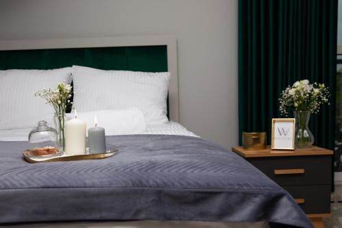 a bed with two candles and a tray with flowers at Wisteria Hotel in Laskowiec