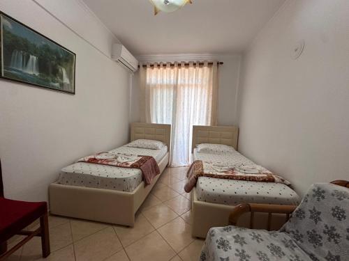 a room with two beds and a chair and a window at Anita Apartment in Përmet
