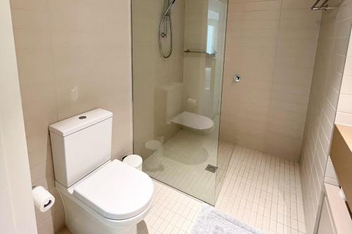 a white bathroom with a toilet and a shower at Docklands Luxury Comfort Apartment in Melbourne