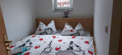 a bed with four pillows with hearts on it at Ferienwohnung in Spreewaldnähe in Kolkwitz