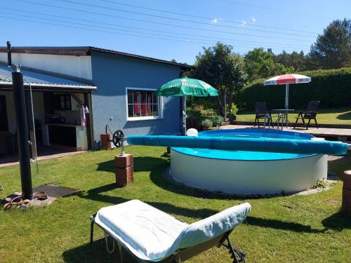 a swimming pool with an umbrella and two chairs and a table at Ferienwohnung in Spreewaldnähe in Kolkwitz