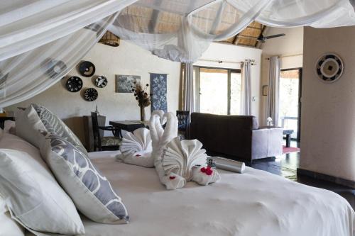 a bedroom with a white bed with pillows at Ezulwini Game Lodges in Balule Game Reserve