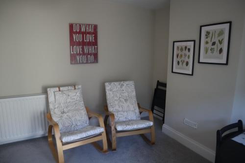 two chairs in a room with two pictures on the wall at 3 Bed home, Stranmillis, Queens Quarter in Belfast