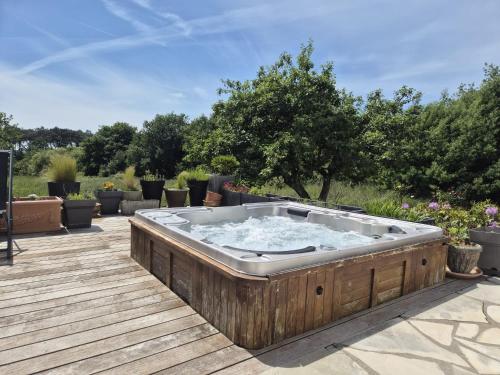 a hot tub sitting on a wooden deck at Ty Nehue - Maison avec jacuzzi in Crach