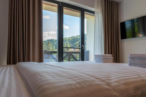 a bedroom with a bed and a large window at Vila Ferdinand - Apartament Iarina in Sinaia