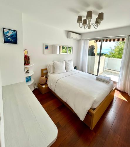 une chambre avec un grand lit blanc et une fenêtre dans l'établissement Appartement Luxe - 3 pièces avec vue mer, piscine et tennis, à Nice