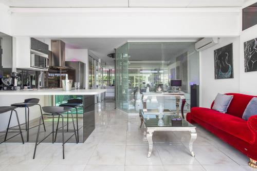 un salon avec un canapé rouge et une cuisine dans l'établissement Village Naturiste R4N - La Villa Shimmer Luxe, au Cap d'Agde