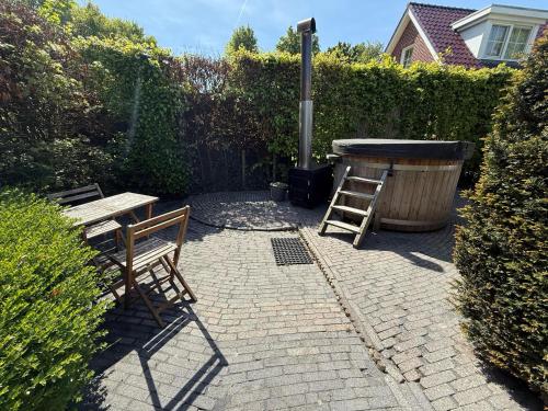 - une terrasse avec 2 chaises, une table et un grill dans l'établissement The Cosy Cottage for Comfort with Sauna and Hottub, à Zeewolde