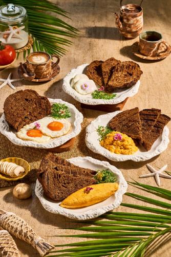 a table with plates of breakfast foods on it at Café del Mar Phuket - Suite & Penthouse in Kamala Beach