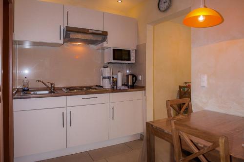 a kitchen with white cabinets and a sink and a table at Familie Schwantes in Buxtehude