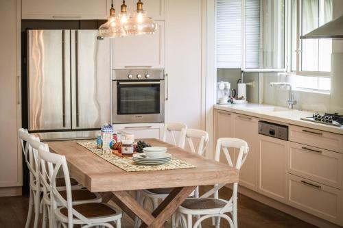 Chic 2BR Apt w Large Windows in Tel Aviv Old North في تل أبيب: مطبخ مع طاولة خشبية مع كراسي بيضاء