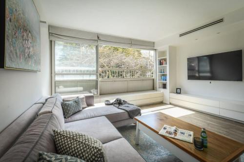 Chic 2BR Apt w Large Windows in Tel Aviv Old North في تل أبيب: غرفة معيشة مع أريكة ونافذة كبيرة