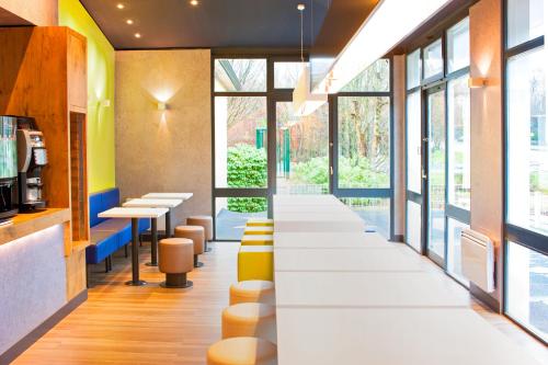 a row of stools in a restaurant with windows at ibis budget Marne la Vallée Bry sur Marne in Bry-sur-Marne