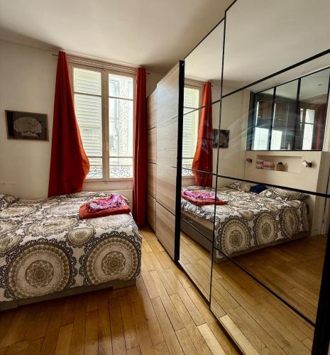 une chambre avec deux lits et un grand miroir dans l'établissement Spacieux et élégant appart Paris, à Paris