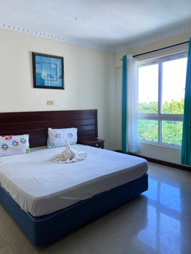 a bedroom with a large bed with a large window at Nyali Sunrise Apartment in Nyali