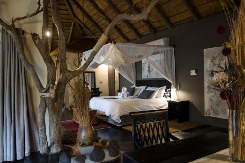 a bedroom with a bed and a tree in it at Ezulwini Game Lodges in Balule Game Reserve