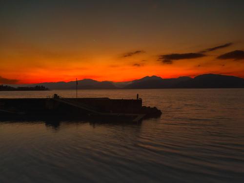 a boat sitting in the water at sunset at Holly Tree Hotel, Swimming Pool & Hot Tub in Glencoe