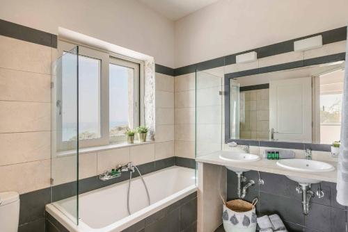 ein Badezimmer mit zwei Waschbecken und einer Badewanne in der Unterkunft Mounda Beach Villa in Ratzaklíon