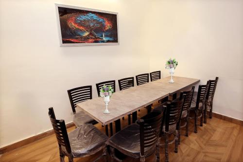 a dining room table with chairs and a painting on the wall at Park Plaza Hotel Near Golden Temple in Amritsar