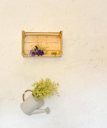 a vase with flowers on a wall with a shelf at Il Giardino del Priore Dimora Rurale in Ugento