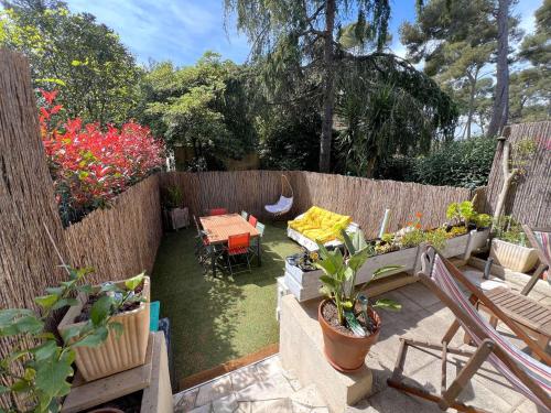 d'un jardin avec une table, des chaises et une clôture. dans l'établissement Le Costabella - Appartement pour 4 personnes à 5 minutes de la plage de l'Almanarre à Hyères, à Hyères