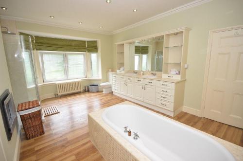 un ampio bagno con vasca e grande specchio di The Sheriff House - Beautiful large property in Wroxham, perfect for family holidays a Wroxham