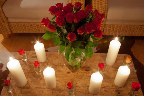 a vase of red roses and candles on a table at Ferienhaus Alpenpanorama Chalet in Mollenberg