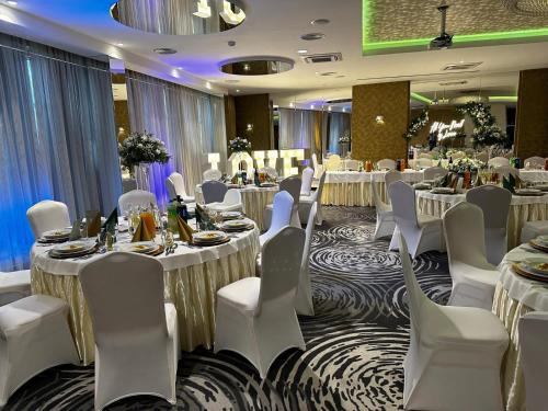a banquet hall with white tables and white chairs at Arena Hotel Spa & Wellness in Tychy