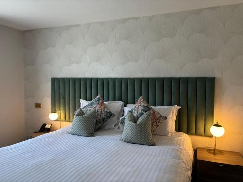 a bedroom with a large bed with a green headboard at Hatherley Manor Hotel & Spa in Gloucester