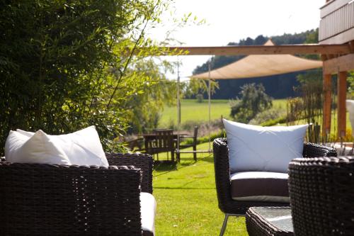 two wicker chairs with white pillows on a lawn at Ferienhaus Alpenpanorama Chalet in Mollenberg