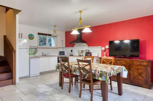 une cuisine avec des murs rouges et une table et des chaises dans l'établissement Maison charmante à Saint-Léonard, à Saint-Léonard