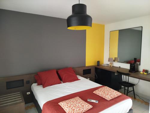 Schlafzimmer mit einem Bett mit roten Kissen und einem Schreibtisch in der Unterkunft Studio avec GRANDE PISCINE, PLAGE Cannelle Caraïbes in Saint-François