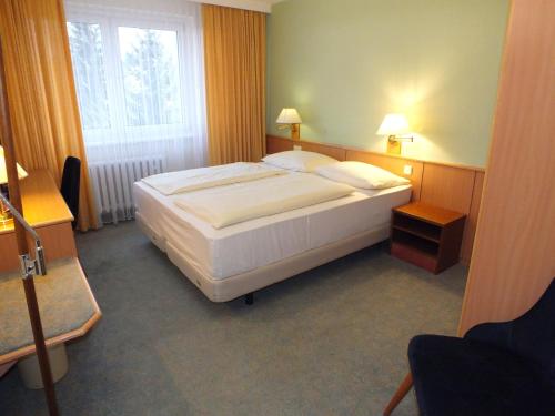 a bedroom with a large white bed with a window at Werrapark Resort Hotel Frankenblick in Masserberg