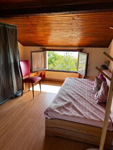 une chambre avec un lit, une chaise et une fenêtre dans l'établissement Maison sur la plage, à Folelli