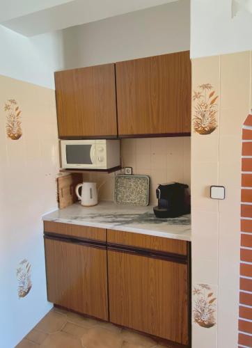 a kitchen with wooden cabinets and a microwave at Family Apartment with Balcony, 5 min from the Beach in Santa Cruz