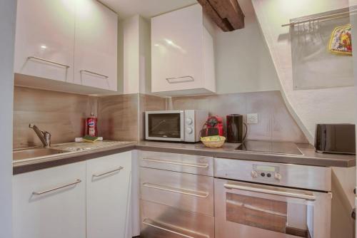 une cuisine avec des armoires blanches et un micro-ondes dans l'établissement Nice atypical apartment, Vieux Lille, à Lille