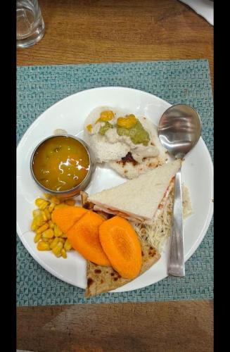 a plate of food with a sandwich and fruit and dips at Hotel Vaarahi Chanda Nagar, Near Hitech City in Hyderabad