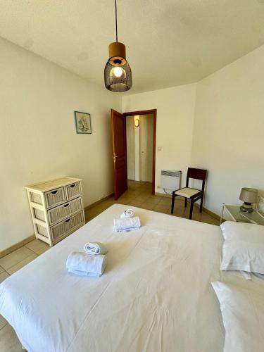 a bedroom with a large white bed with two towels on it at Grand appartement central - Propriano in Propriano