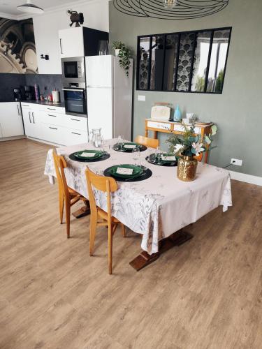 a dining room table with a white table cloth and chairs at Le Familia in Guer