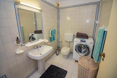 a bathroom with a sink and a washing machine at Apartamento Casa do Mar Praia da Luz in Luz