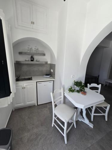 biała kuchnia z białym stołem i krzesłami w obiekcie Anthonas Apartments w Imerovíglion