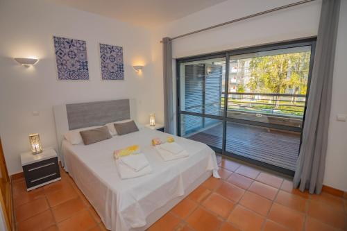 a bedroom with a white bed and a large window at Corbo apartament in Bicas