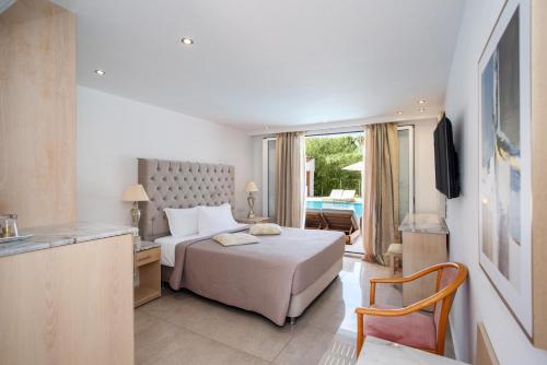 a hotel room with a bed and a desk and a television at Cavomarina Beach- Adults Only in Kavos