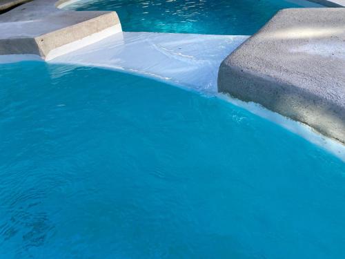 a pool of blue water next to a concrete curb at Bahia Selvatica Lodge in Uvita