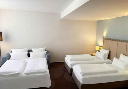 two beds in a room with white sheets at Garner Hotel Essen - Handelshof by IHG in Essen
