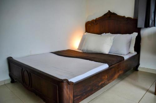 a bed with a wooden frame and white pillows at Iris Pousada Hostel Arraial do Cabo in Arraial do Cabo
