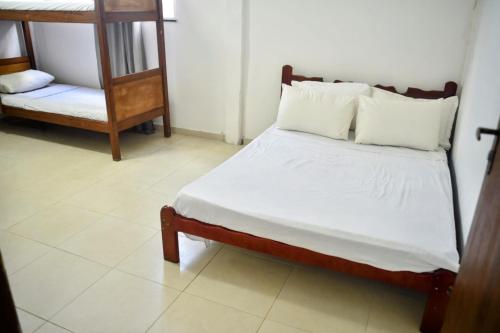 a bed with white sheets and pillows in a room at Iris Pousada Hostel Arraial do Cabo in Arraial do Cabo